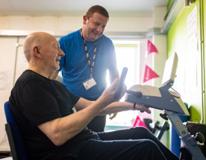 Personal trainer with a man on a gym exercise machine 